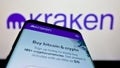 Smartphone with website of US crypto company Payward Inc. (Kraken) on screen in front of business logo.