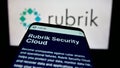 Smartphone with website of US data security company Rubrik Inc. on screen in front of business logo.