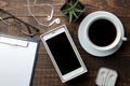 Smartphone white and a cup with coffee glasses and a blank on a brown wooden table. view from above Royalty Free Stock Photo