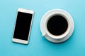 Smartphone. White phone and a cup of coffee on a bright light blue background. top view Royalty Free Stock Photo