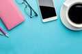 Smartphone. White phone and a cup of coffee and a notebook with glasses on a bright light blue background. top view Royalty Free Stock Photo