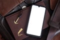 A smartphone with a white screen on a leather bag with a note pad and various scattered things Royalty Free Stock Photo