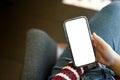 A smartphone white screen mockup is in a woman`s hand over her laps. cropped image Royalty Free Stock Photo