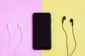 Smartphone and Wired earphones on pink and yellow background Royalty Free Stock Photo