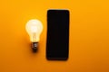 Smartphone with a yellow light bulb AI generated