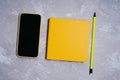 Smartphone in a yellow silicone case, a simple pencil and notepad or sketchbook Royalty Free Stock Photo