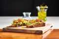 smashed avocado on rye, drizzled with olive oil, on a wooden board