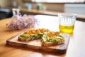 smashed avocado on rye, drizzled with olive oil, on a wooden board