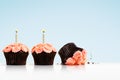 Smashed cupcake in row of cupcakes with candles on blue Royalty Free Stock Photo