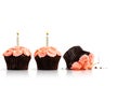 Smashed cupcake in row of cupcakes with candles isolated on white Royalty Free Stock Photo