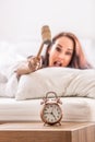 Smashing of alarm clock with the hammer by a woman reaching out from the bed Royalty Free Stock Photo
