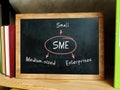 SME Small Medium-sized Enterprises note. Still life with stack of colorful books and blackboard Royalty Free Stock Photo