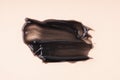 Smear of a black magnetic, jelly or charcoal mask on a beige background.