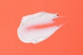 Smear of white cosmetic cream on the orange background,abstract form
