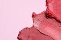 Smears of beautiful lipsticks on pink background, closeup