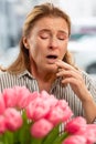 Woman sneezing after smelling flowers having allergy Royalty Free Stock Photo