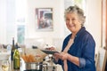 It smells so delicious in here. Portrait of a senior woman using a digital tablet while cooking in her kitchen. Royalty Free Stock Photo