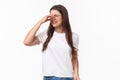 Smells disgusting. Portrait of disgusted and displeased young beautiful girl in glasses, shut nose with fingers and look