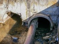 Smelly sewage water flowing trough concrete and iron pipes in a concrete pit