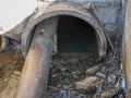Smelly sewage water flowing trough concrete and iron pipes in a concrete pit