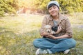 Smile Asian owner carrying, hugging adorable puppy dog on her sitting green grass backyard lawn