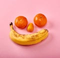 Smile of banana and tangerines on a pink background