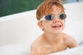 Smile, bath and a boy in swimming goggles having fun while cleaning for natural hygiene in water. Children, soap and Royalty Free Stock Photo