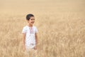 A smile boy holds wheat spikes on the field