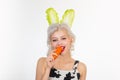 Smile easter. Cute bunny rabbit. Young woman with banny ears eat carrot. Easter bunny dress.