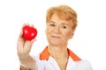 Smile elderly female doctor or nurse holding red toy heart