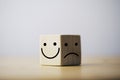 Smile face in bright side and sad face in dark side on wooden block cube for positive mindset selection concept Royalty Free Stock Photo