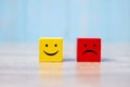 Smile face on yellow wood cube and sad face icon on red wood cube. Service rating, ranking, customer review, satisfaction and Royalty Free Stock Photo