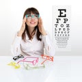 Smile female face chooses spectacles on eyesight test chart back Royalty Free Stock Photo