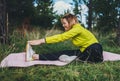 Smile girl exercising outdoors in green park, activity with stretch arms and legs. Young fitness woman doing stretching exercises Royalty Free Stock Photo