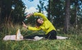 Smile girl exercising outdoors. Young fit woman doing stretching exercises  training outside in green park. Sport woman play yoga Royalty Free Stock Photo