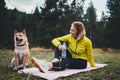 Smile girl with pet together relax after exercising outdoors on yoga mat, shiba inu dog on nature fitness woman drink water