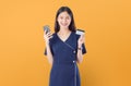 Smile happily Asian woman blue dress holding smartphone and credit card shopping online on orange background. Royalty Free Stock Photo
