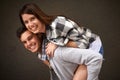 Smile, hug and portrait of couple piggyback ride, bond and having playful fun isolated on grey background. Support Royalty Free Stock Photo