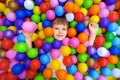 Smile kid lying colorful plastic balls pool. Playroom kids ball pit. Colorful balls dry pool kindergarten playground