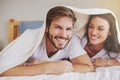 Smile, love and couple with blanket for relaxing, bonding and resting on bed together at home. Happy, romantic and young Royalty Free Stock Photo