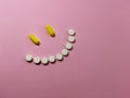 Smile made of pills on an pink background