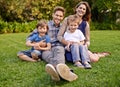 Smile, nature and portrait of children with parents relaxing on grass in outdoor park or garden. Happy, love and boy Royalty Free Stock Photo