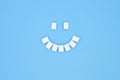 Smile symbol, composed of cubes of sugar on blue background. Concept of sugar leading to caries