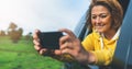 Smile tourist girl in an open window of a auto car taking photo selfie on mobile smart phone, person looking on camera gadget Royalty Free Stock Photo