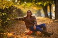 Smile woman sitting on the pumpkin on the autumanl maple leaves Royalty Free Stock Photo