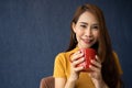 Smile young Asian woman holding a red cup and enjoying drinking warm coffee in the morning, Concept of relaxation in leisure and Royalty Free Stock Photo