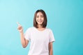 Smile young Asian woman standing on a blue background and sideways pointing.