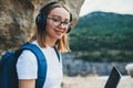 Smile young girl tourist with backpack enjoying summer holidays listen music in headphones and laptop in nature, woman copywriter Royalty Free Stock Photo