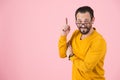 Bearded fashion man pointing up with glasses on nose. Man get the idea isolated in studio on pastel pink background