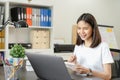 Smiley Asian woman hand holding book and pen with note text form learning on laptop in house.